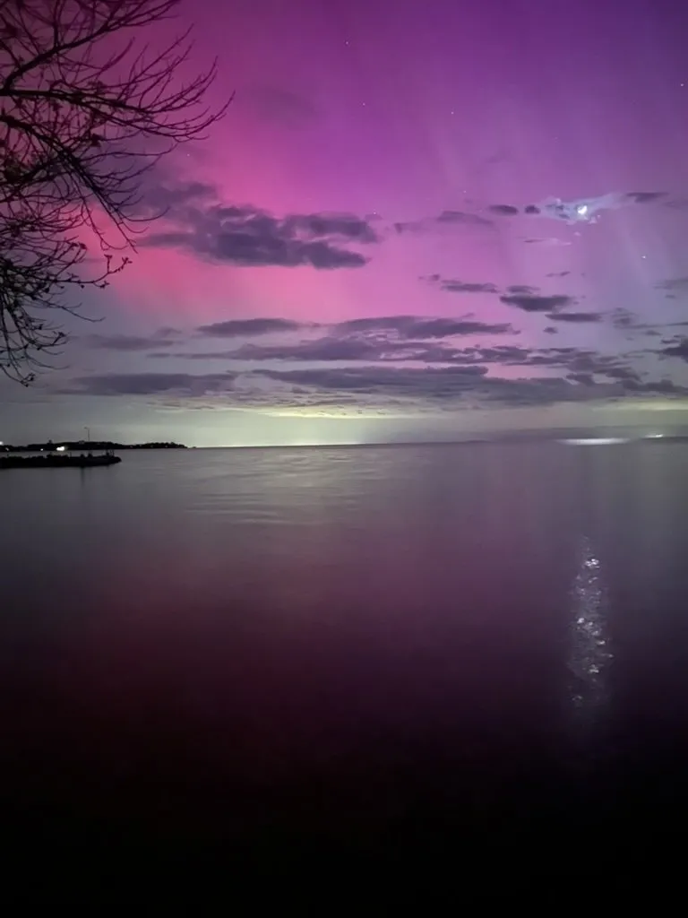Pink northern lights over calm water