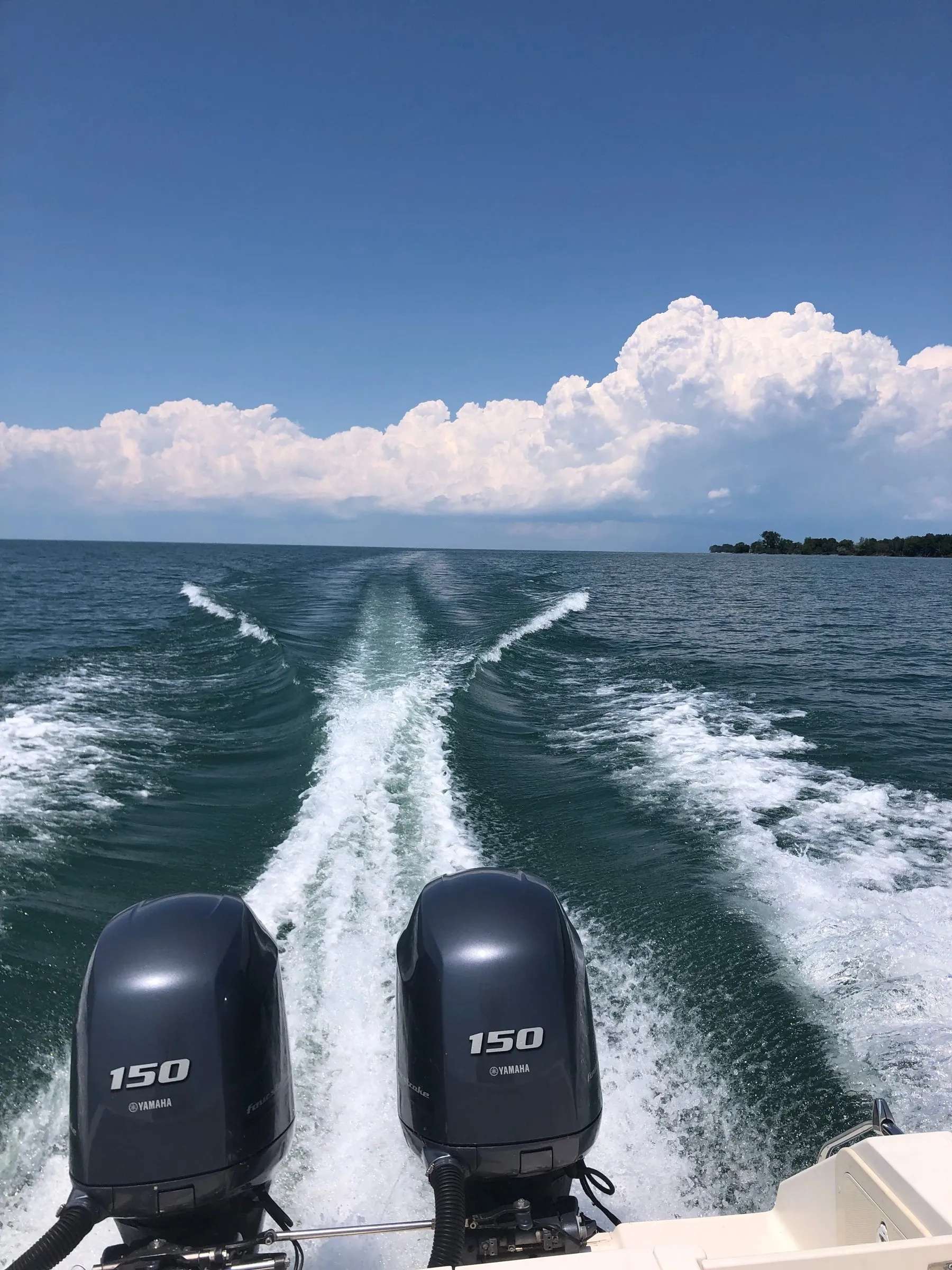 Twin outboard motors throwing a white wake across turquoise water