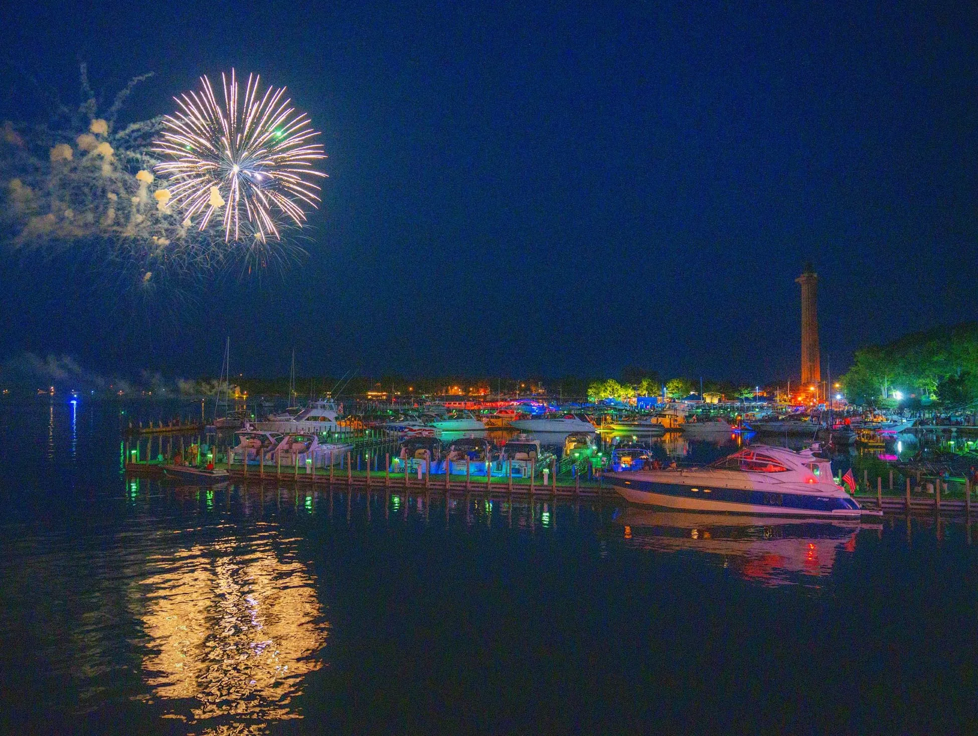 Fireworks over a lit-up harbor full of boats