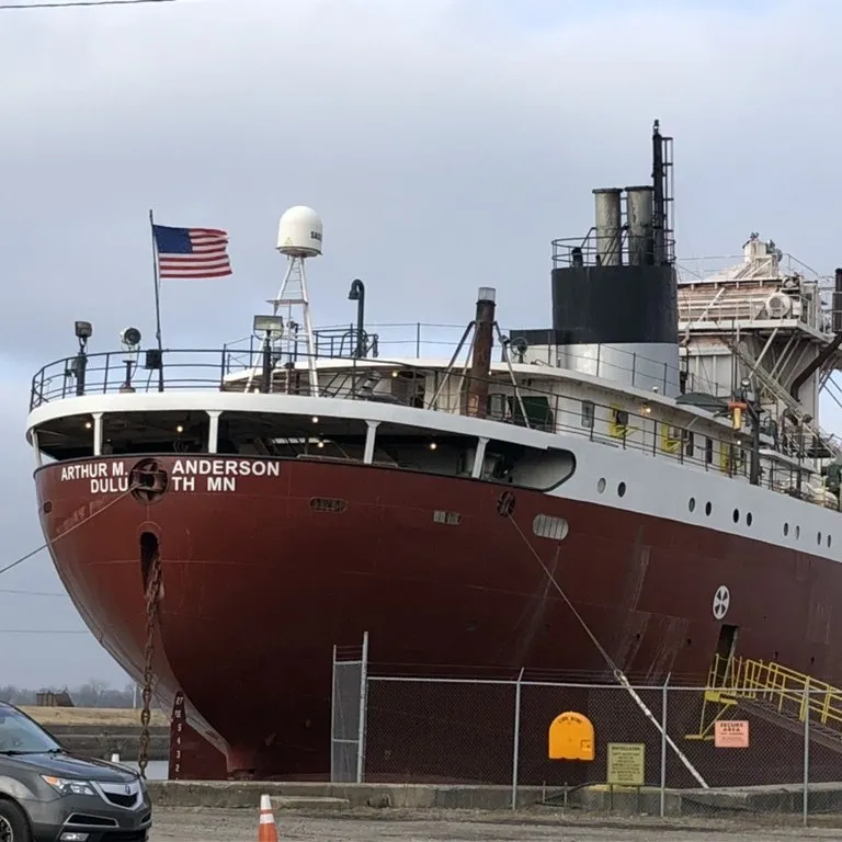 A long red lake freighter tied up at a dock