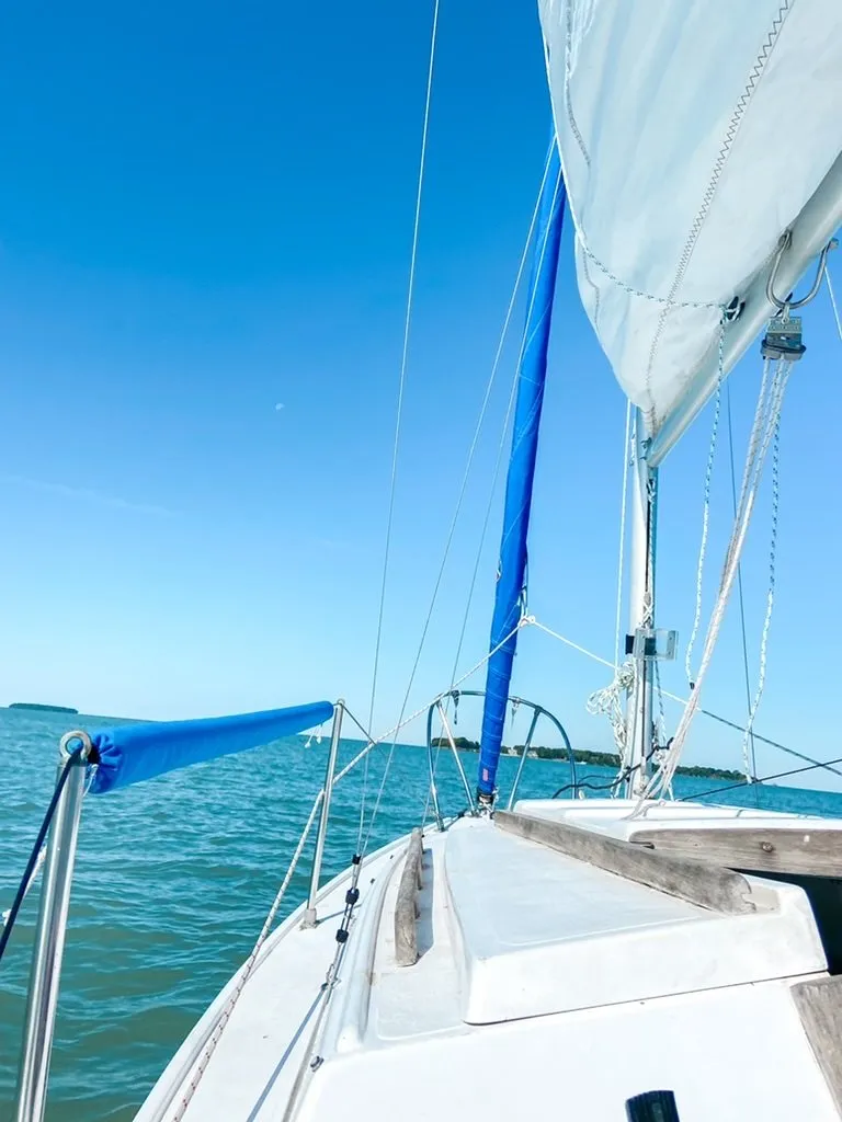 The bow of a sailboat under sail on blue-green water